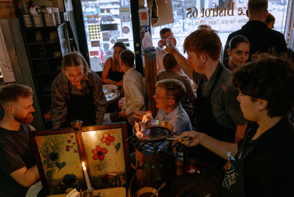 En tjener flamberer nede ved nogle gæsters bord