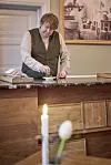 Claus Henriksen står bag trædisk og anretter mad i roligt restaurantmiljø.