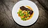 Hovedret med grillet rødspætte, ærter og svampe i sauce på hvid tallerken