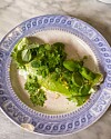 Grøn omelet med friske urter på blåhvid tallerken på marmorbord