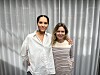 To kvinder står tæt sammen foran et lyst gardin og kigger mod kameraet