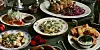 Festligt julebord med stegt fjerkræ, rødkål, kartofler og flere småretter på et grønt dugklædt bord.