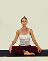 Person sidder krydsbenet på yogamåtte i oprejst meditationsstilling